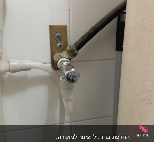 צינור ומחבר על קיר אריחים לבנים